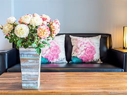 Vase with roses and floral cushions in background